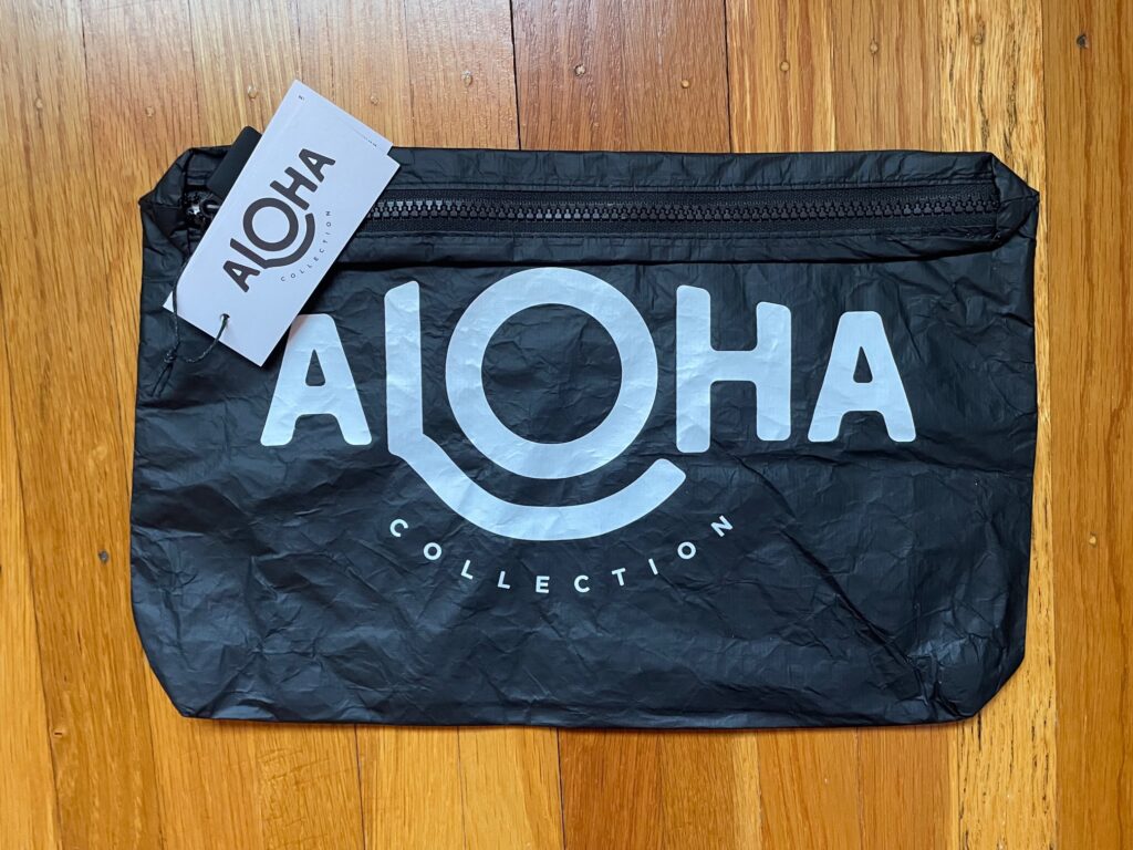 Photo of black Aloha Collection bag with the logo "Aloha Collection" on it in white letters. 