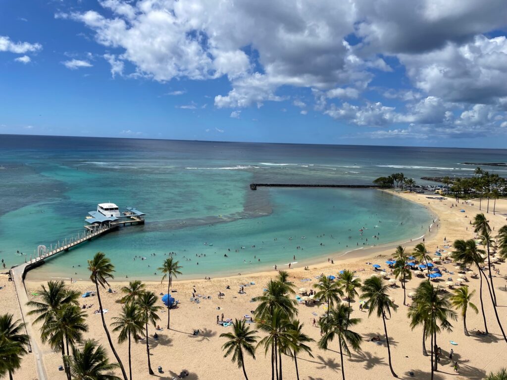 Overlooking the beach in Waikiki, Hawaii with gold sand, palm trees and blue water.