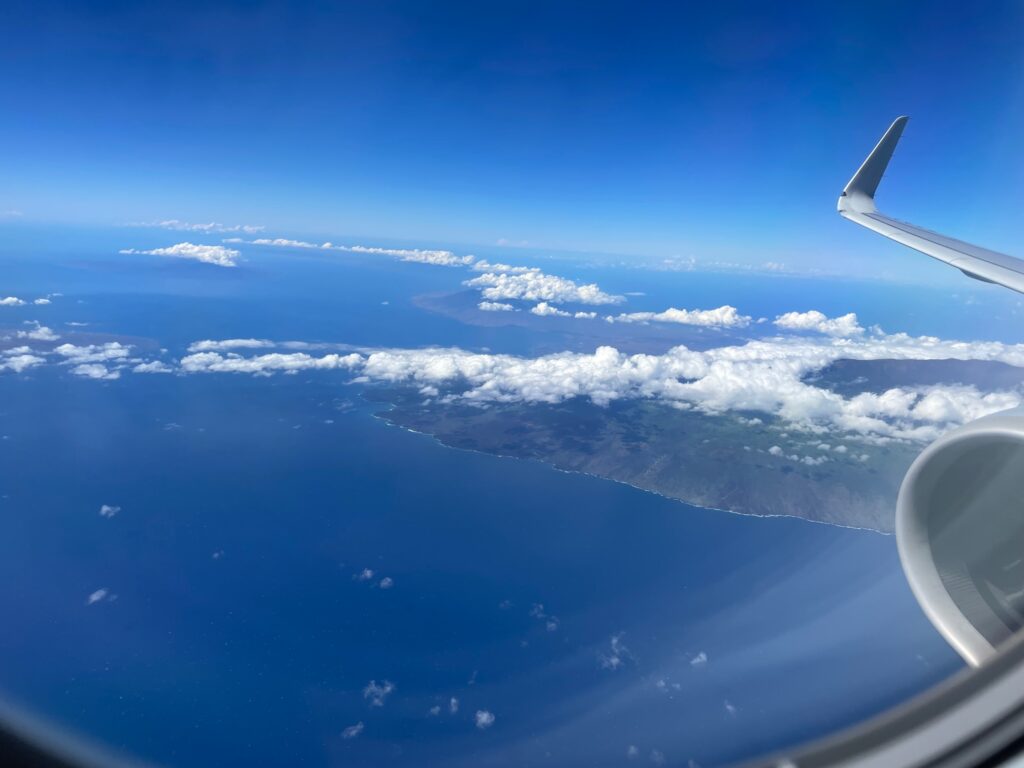 How long is a flight to Hawaii? View over Hawaii. Photo taken from the airplane with the wing in the forefront and the island below. 