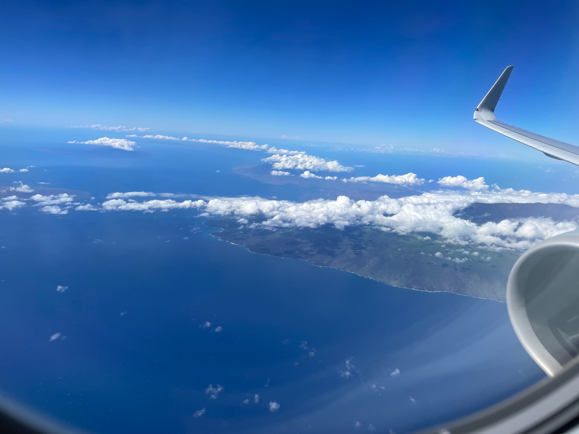 View of Hawaii from the airplane. Wing is visible and island below.