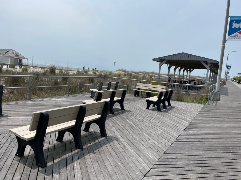 Ventnor City, NJ boardwalk with benches overlooking the beach and the fishing pier. 