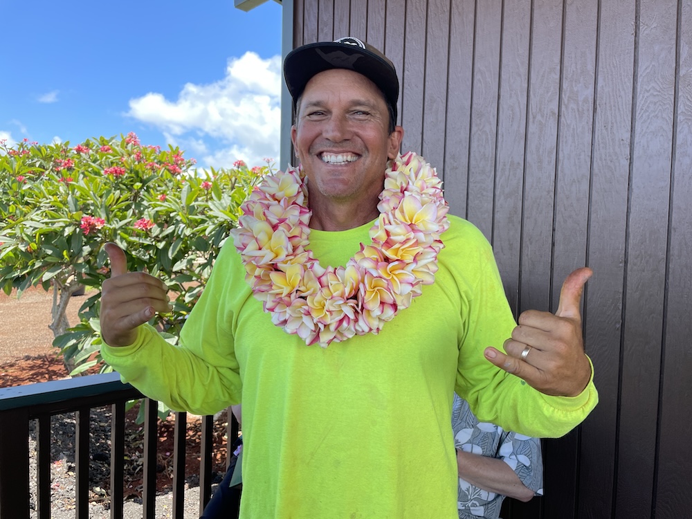 Clark Little wearing a flower lei and yellow shirt at Little Plumeria Farms. Photo taken by Marla Cimini, author of this post. 