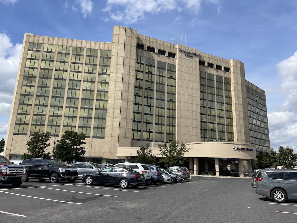 View of Doubletree hotel in Cherry Hill with blue skies. This is a high-rise building and the view is from the parking lot. 